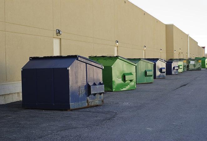 a construction worker empties a wheelbarrow of waste into the dumpster in Davie